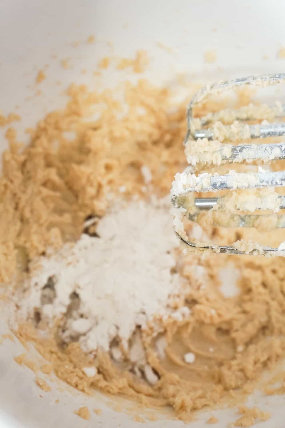 flour added to cookie dough mixture in a mixing bowl