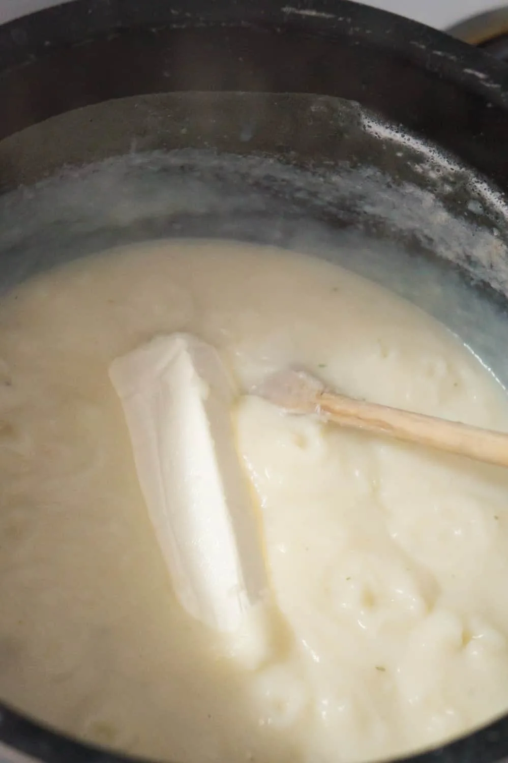 a brick of cream cheese in a pot of potato soup