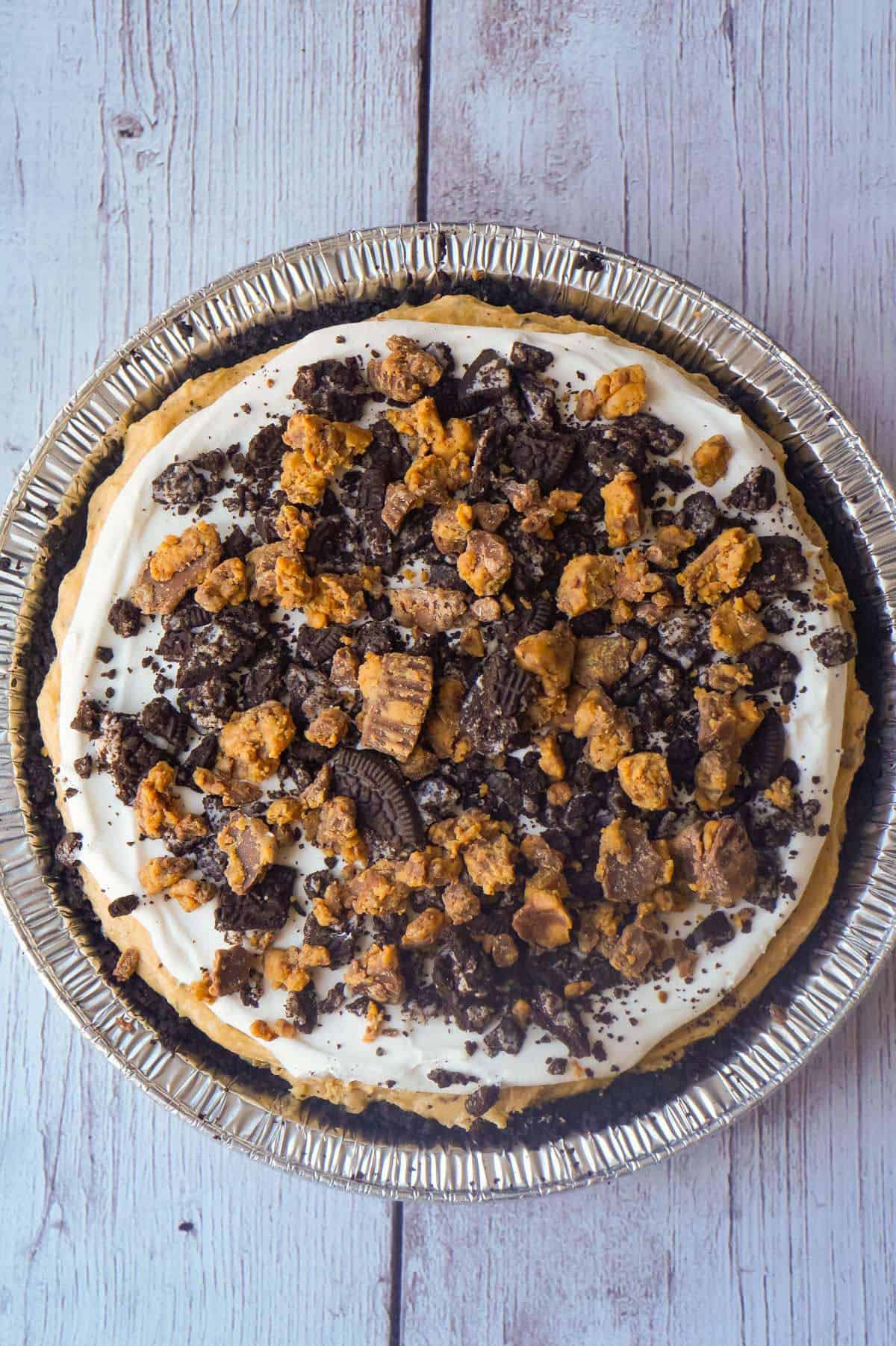 No Bake Oreo Peanut Butter Cup Cheesecake is a quick and easy dessert recipe perfect for any occasion. An Oreo cookie pie crust is filled with a delicious peanut butter and cream cheese mixture loaded with pieces of Reese's Peanut Butter Cups and Oreo cookies. This chocolate peanut butter dessert is perfect for summer.