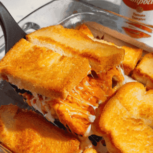 Tomato Soup & Bacon Grilled Cheese Casserole combines two comfort food favorites in one easy family dinner! This cheesy baked sandwich casserole layers buttery bread with shredded cheddar cheese, condensed tomato soup, crispy bacon and melty mozzarella for a golden, gooey meal everyone will want seconds of. With just 10 minutes of prep, this easy casserole recipe is perfect for busy weeknight dinners, weekend lunches or feeding hungry kids. If you love grilled cheese and tomato soup, bacon grilled cheese sandwiches or simple comfort food recipes, save this delicious twist for your meal plan. Made with everyday ingredients in a 9x13 baking dish, this grilled cheese casserole serves six and brings big flavor with very little effort!