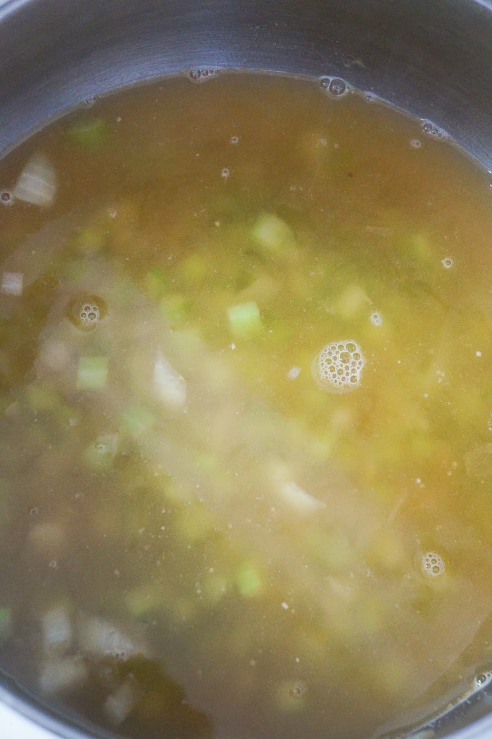 chicken broth in a pot with diced celery and diced onions