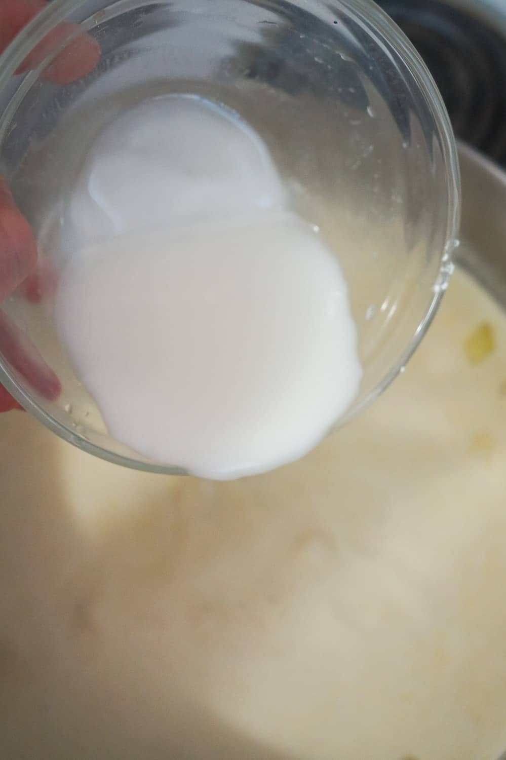 corn starch and water mixture being poured into soup