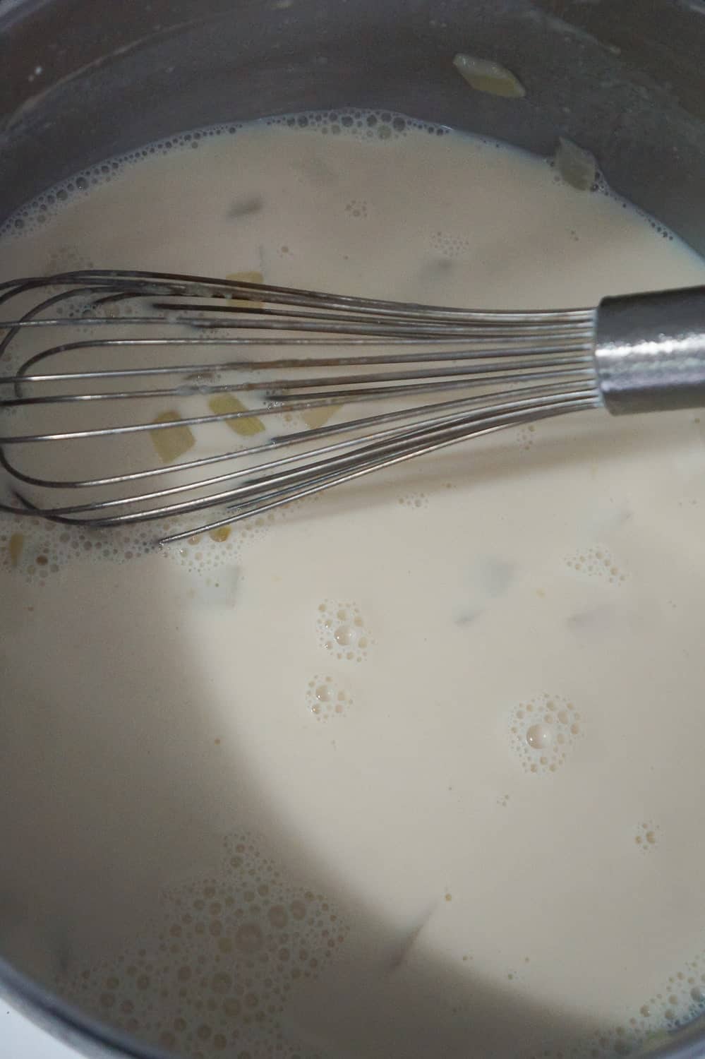 milk and chicken broth in soup pot with whisk