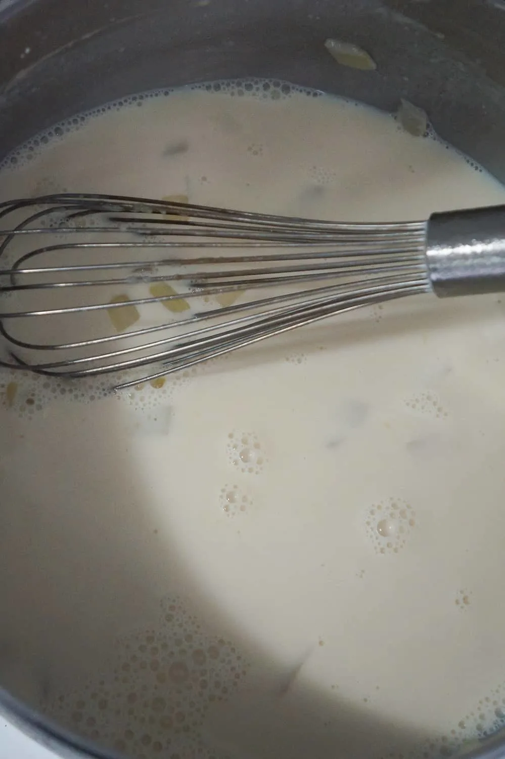 milk and chicken broth in soup pot with whisk