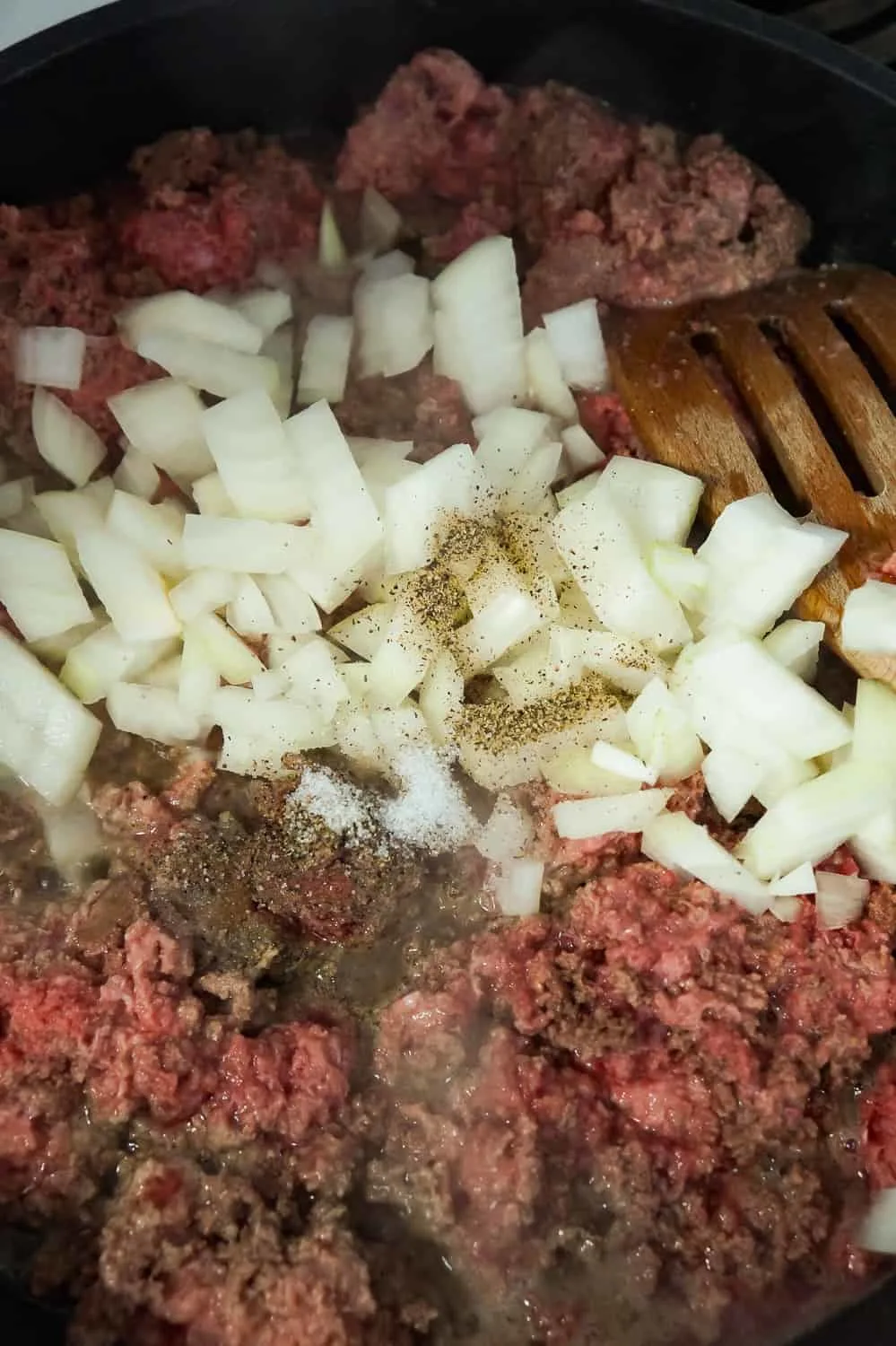 diced onions and ground beef cooking in a frying pan