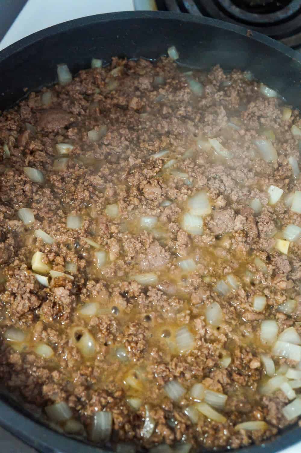 cooked ground beef and onions in a frying pan with gravy