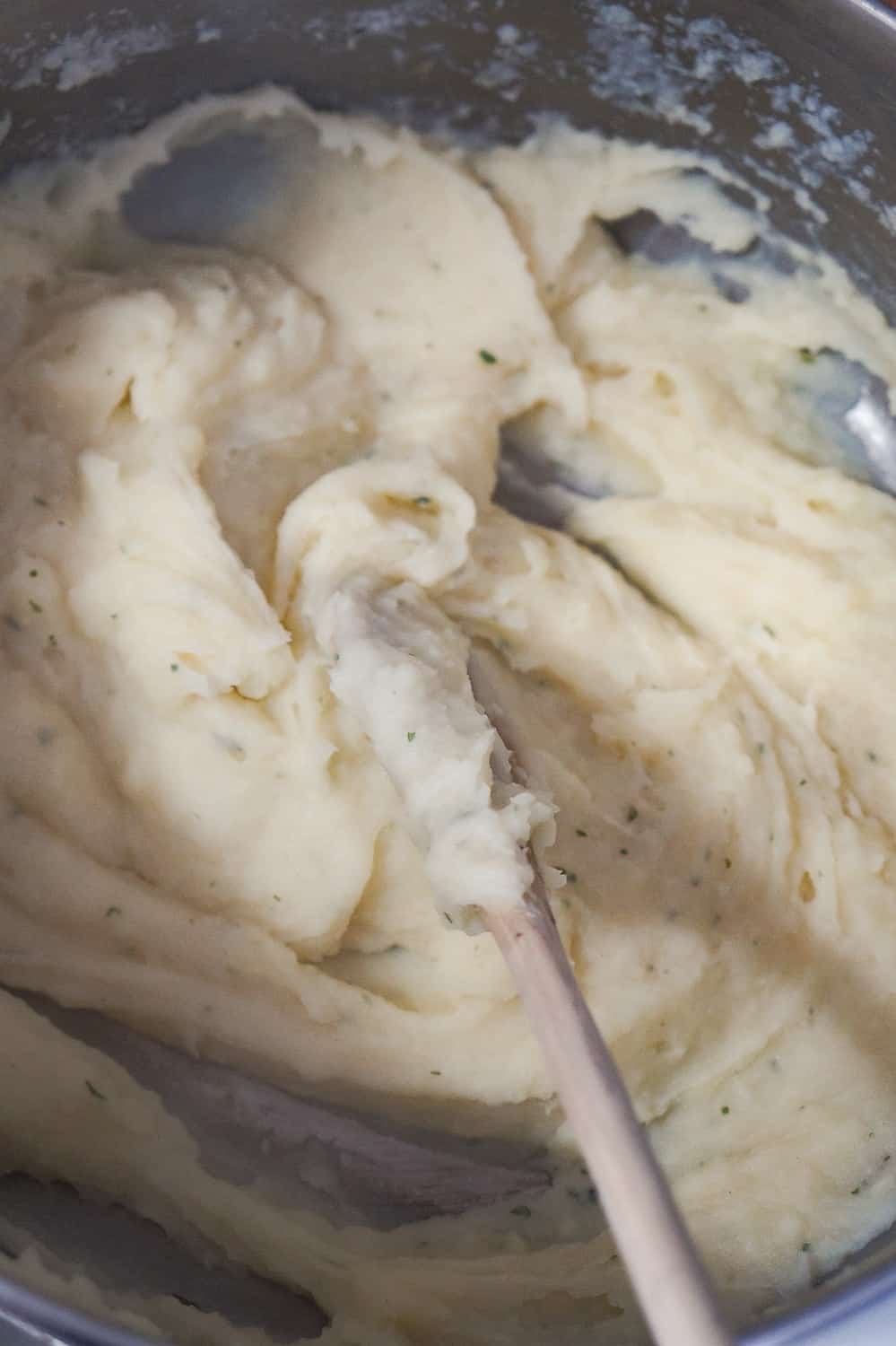 cream mashed potatoes in a saucepan with a wooden spoon