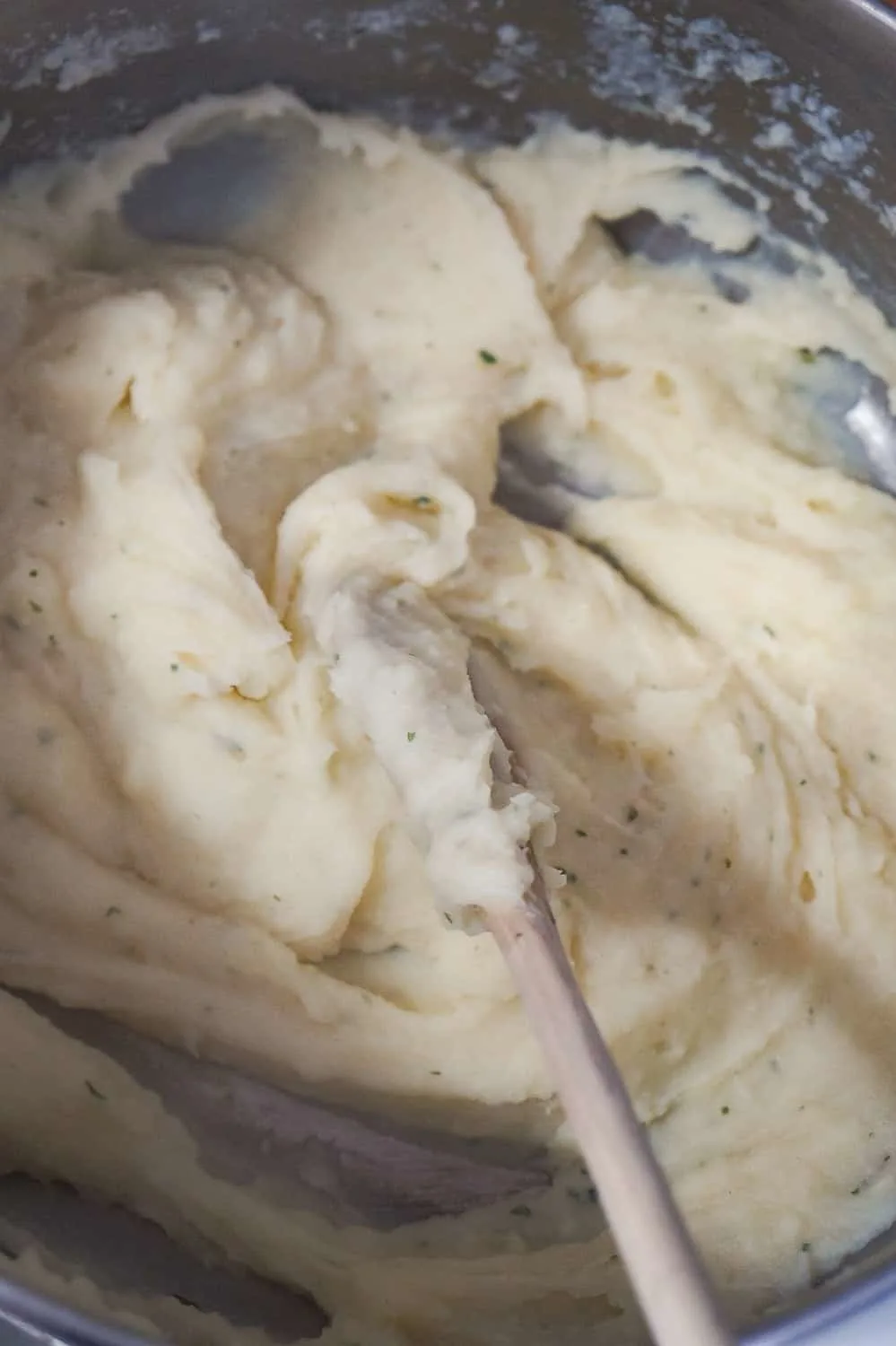 cream mashed potatoes in a saucepan with a wooden spoon