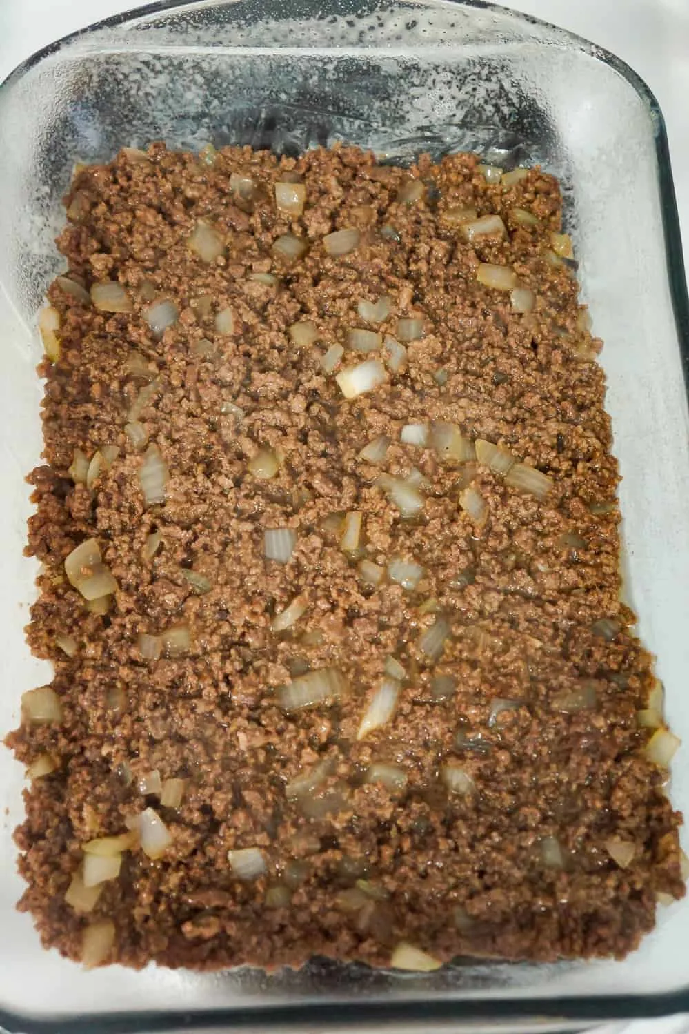 cooked ground beef and diced onions in a baking dish