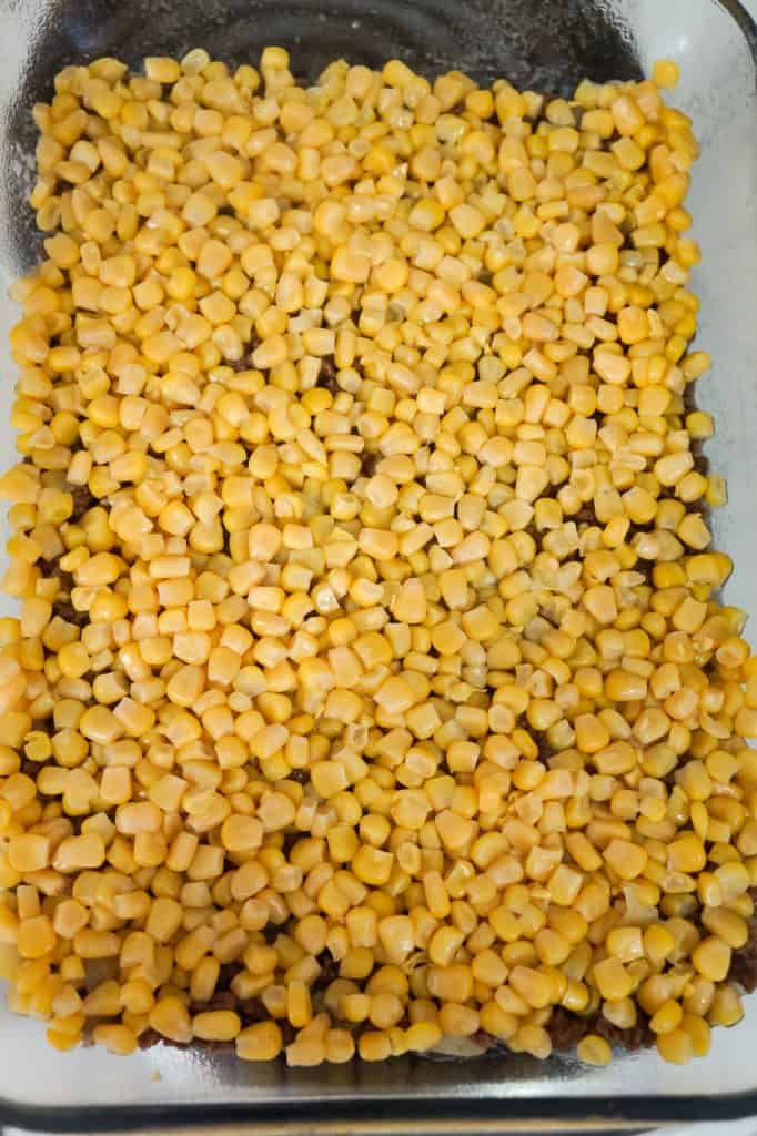 corn spread on top of ground beef in a baking dish