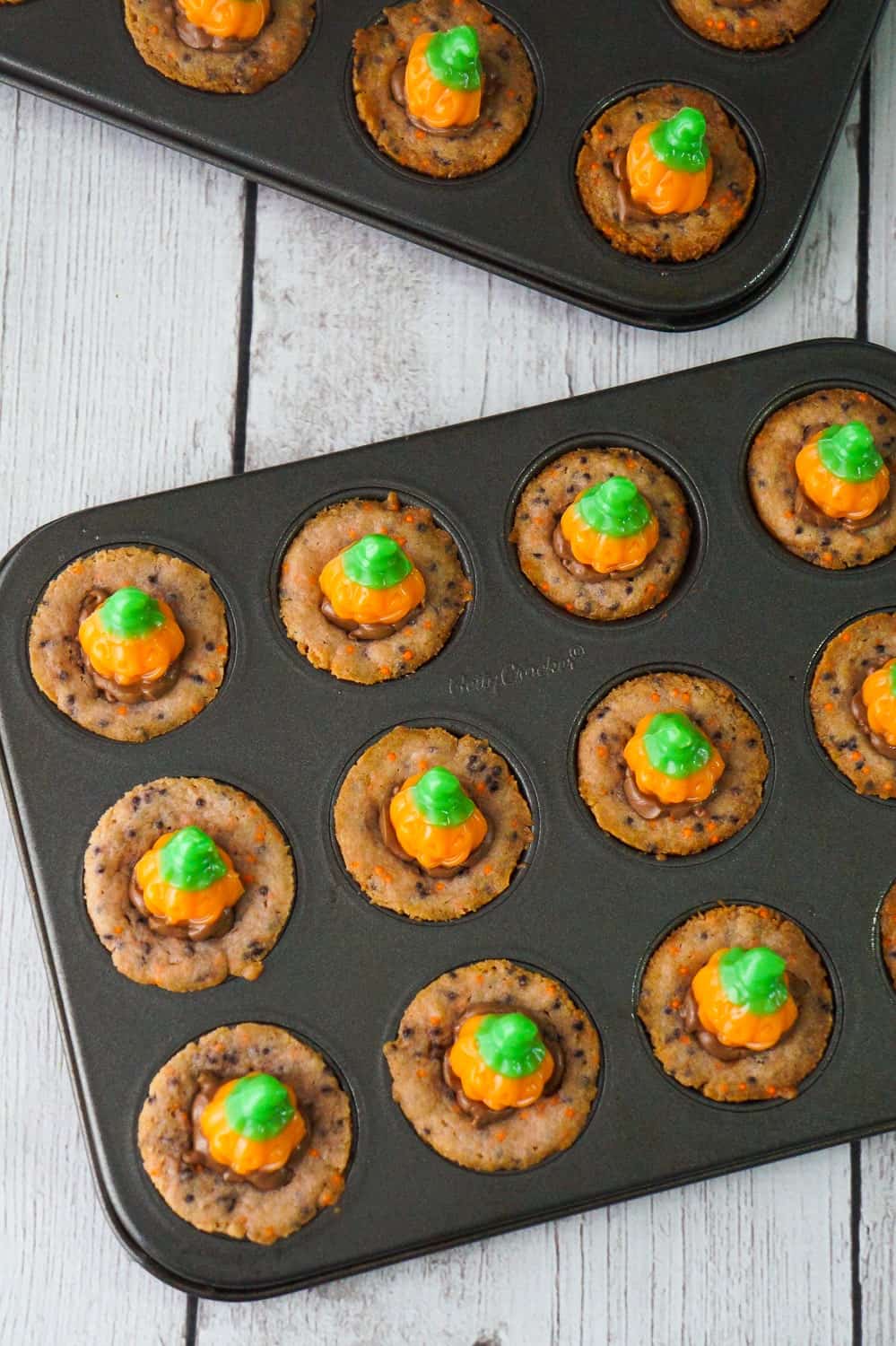 Halloween Sugar Cookie Cups are an easy dessert recipe your kids will love. These cute Halloween cookies are filled with milk chocolate and topped with pumpkin gummy candies.