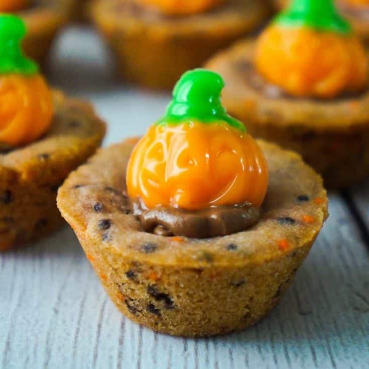 Halloween Sugar Cookie Cups are an easy dessert recipe your kids will love. These cute Halloween cookies are filled with milk chocolate and topped with pumpkin gummy candies.