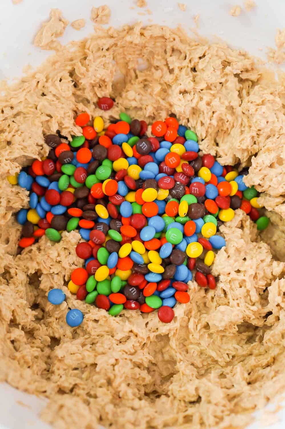 mini M&Ms added to monster cookie dough in mixing bowl