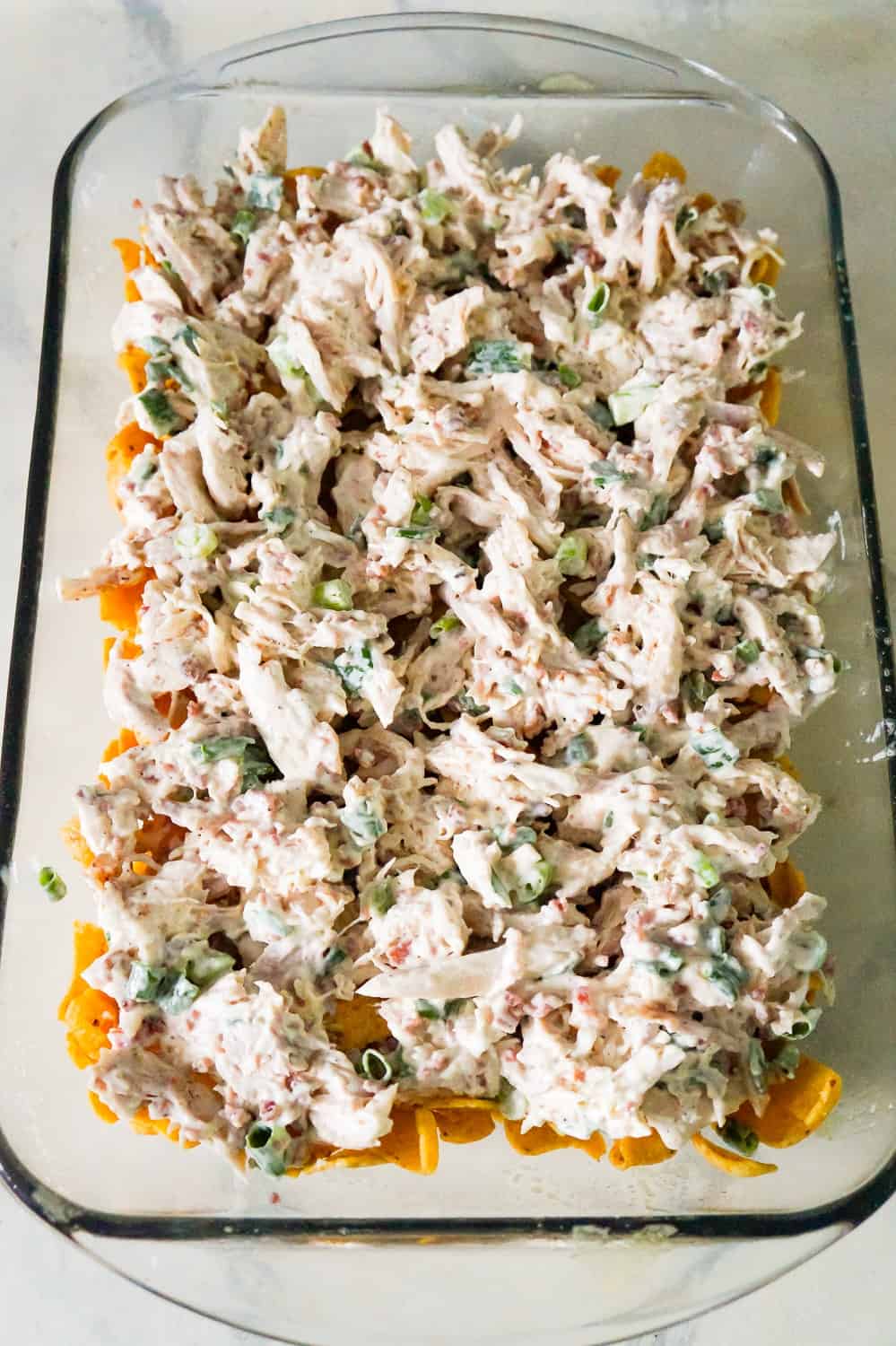 chicken bacon ranch mixture on top of Frito's corn chips in a baking dish