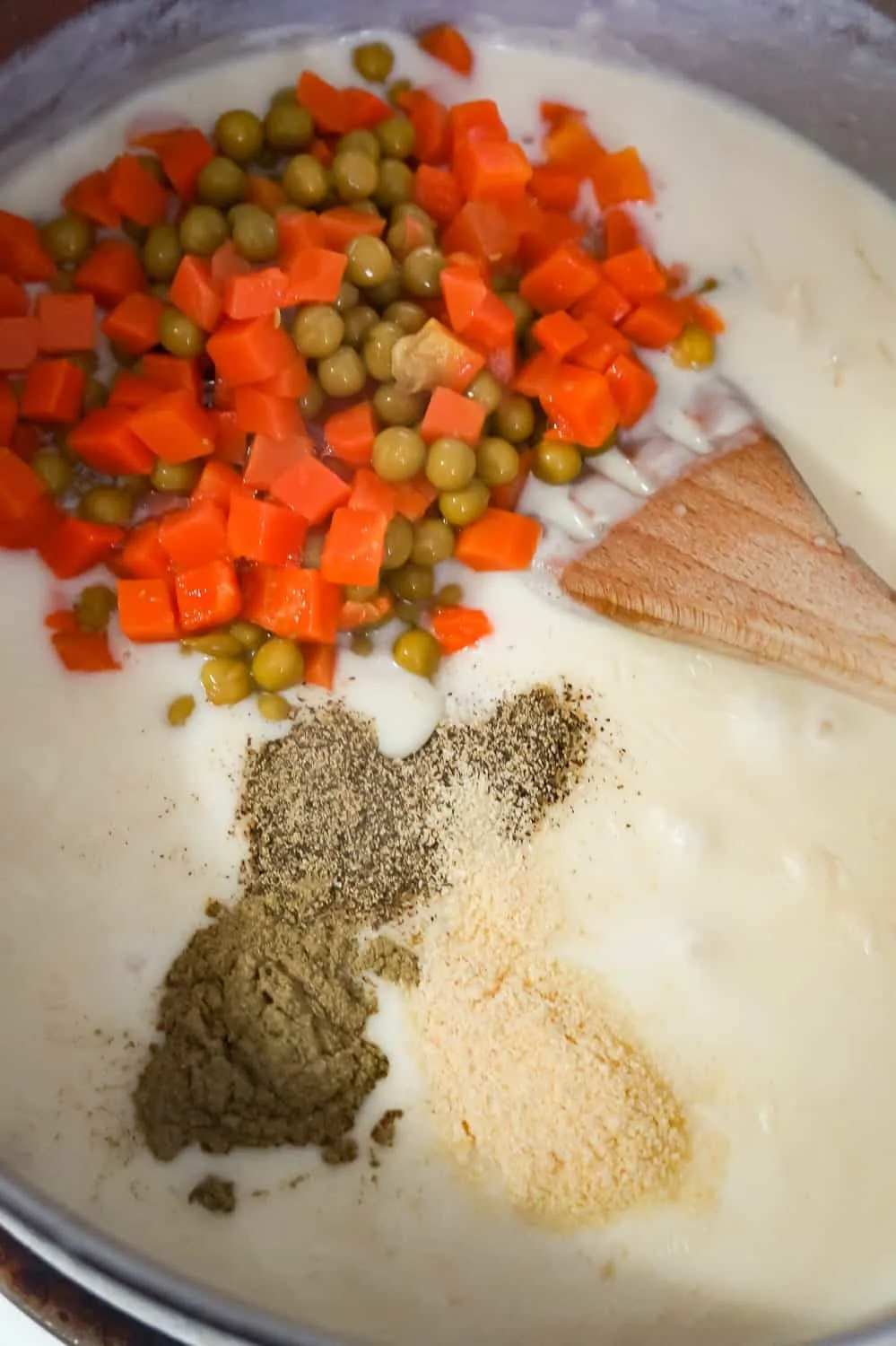 canned peas and carrots, salt, pepper and onion powder being added to creamy turkey soup