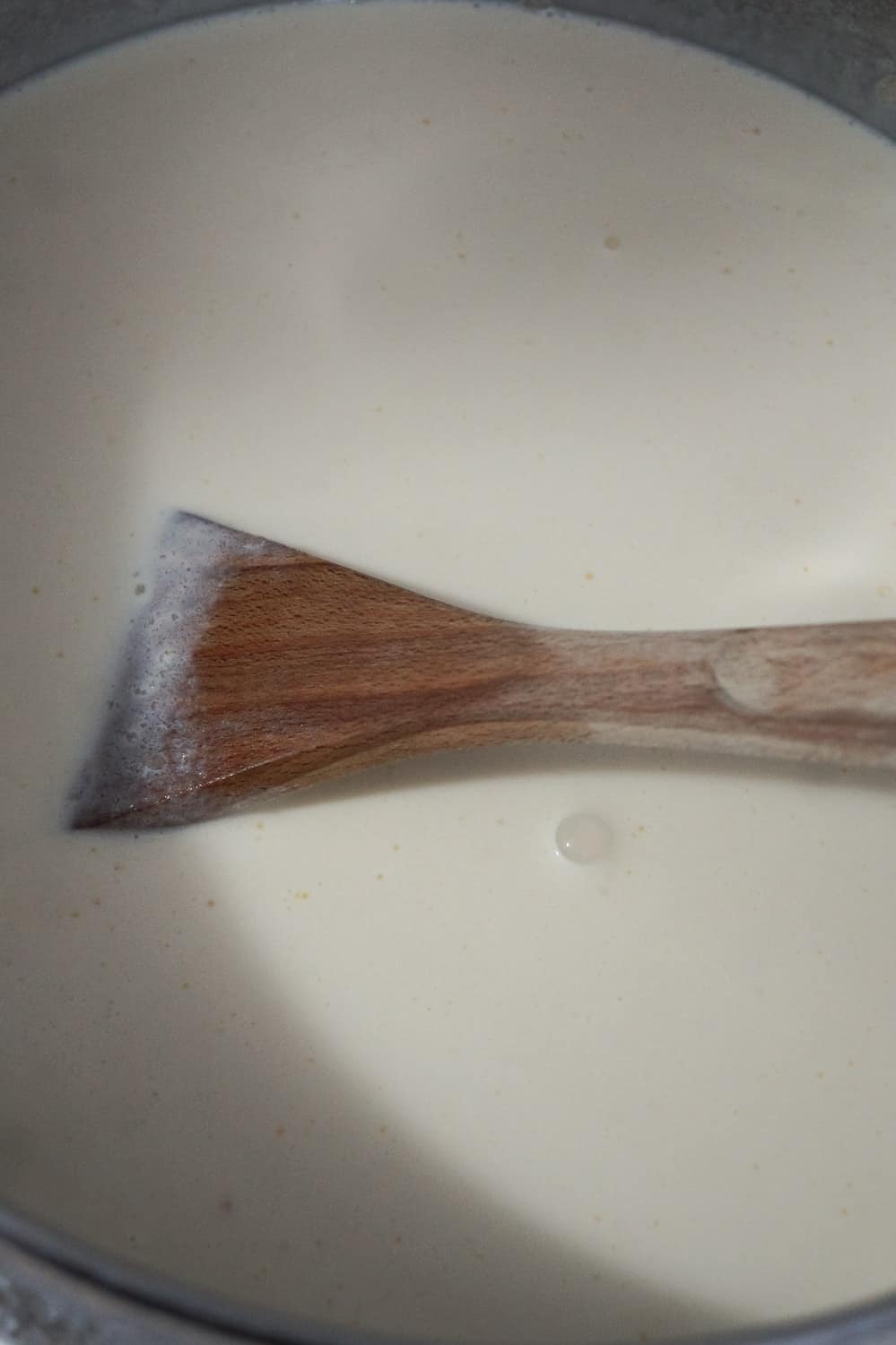 heavy cream in a pot with a wooden spoon