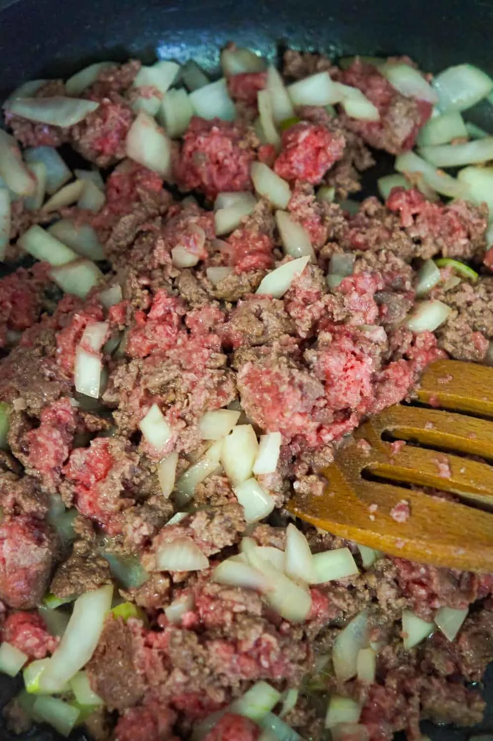 ground beef and diced onions cooking a frying pan