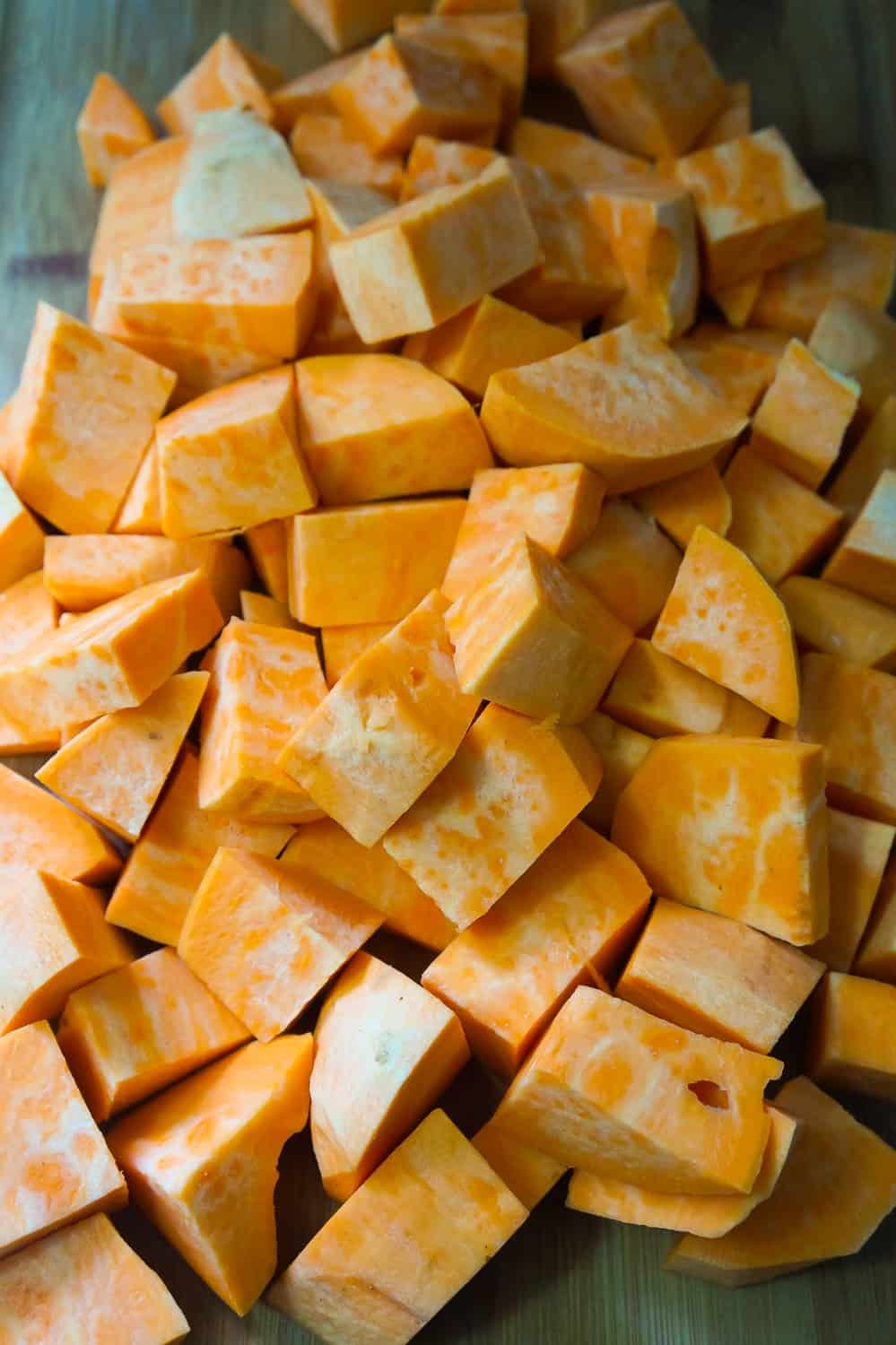 peeled and chopped sweet potatoes on a cutting board