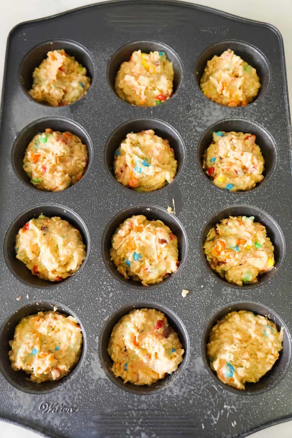 monster cookie muffin batter in a muffin tin