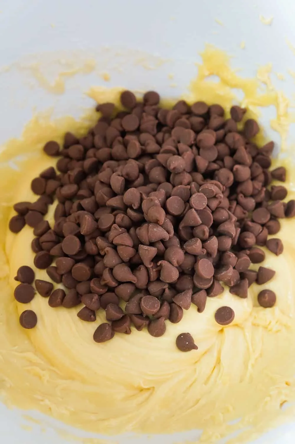 milk chocolate chips on top of cake batter in a mixing bowl