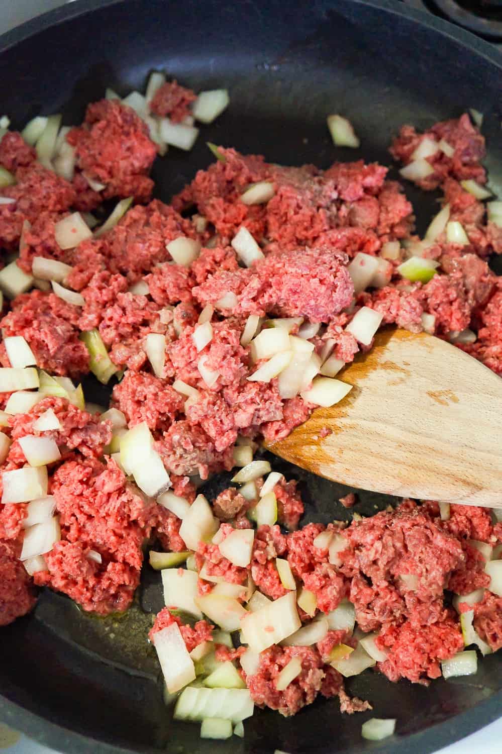 ground beef and diced onions in a frying pan