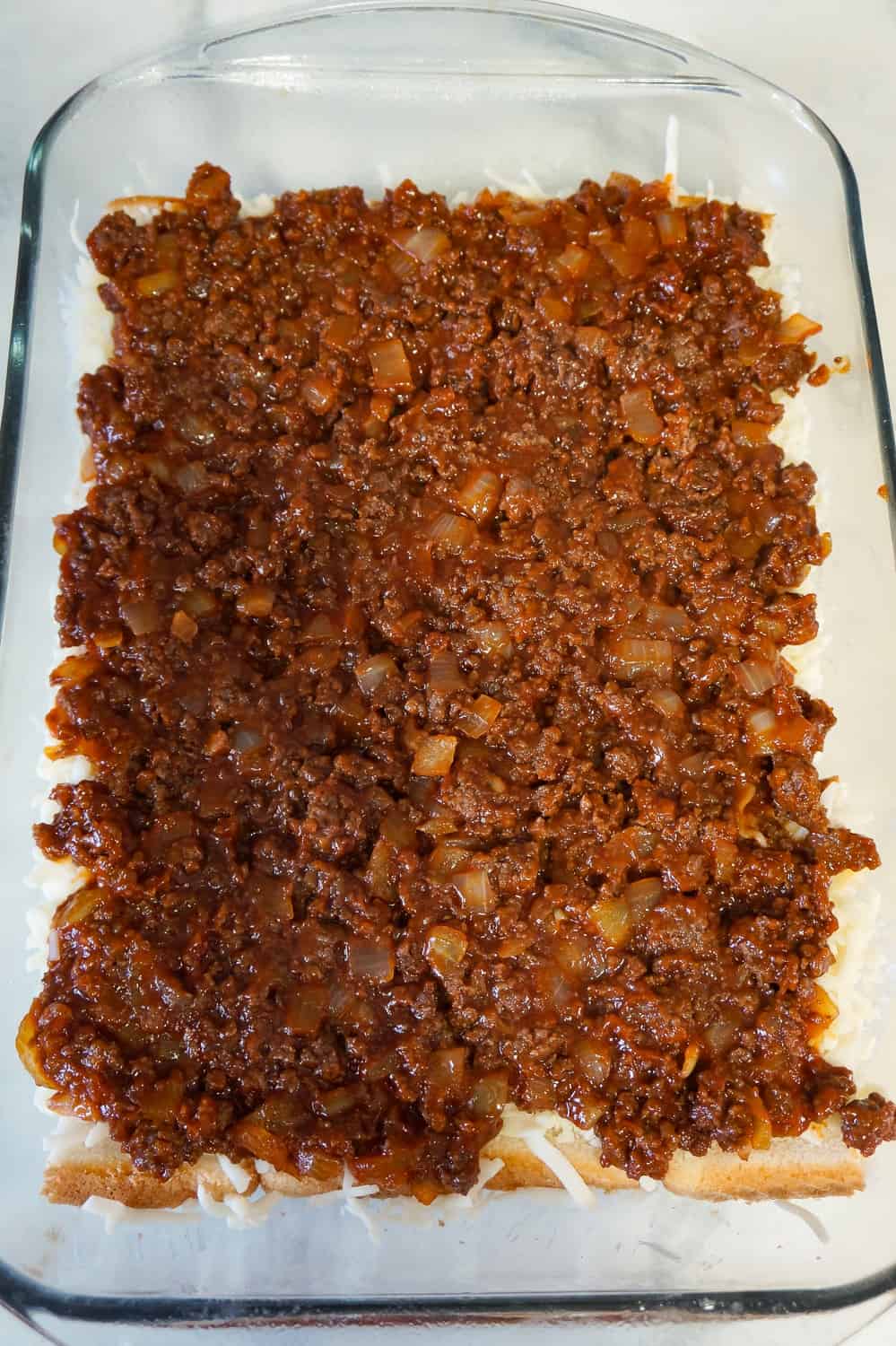 sloppy joe mixture spread over bread in a baking dish