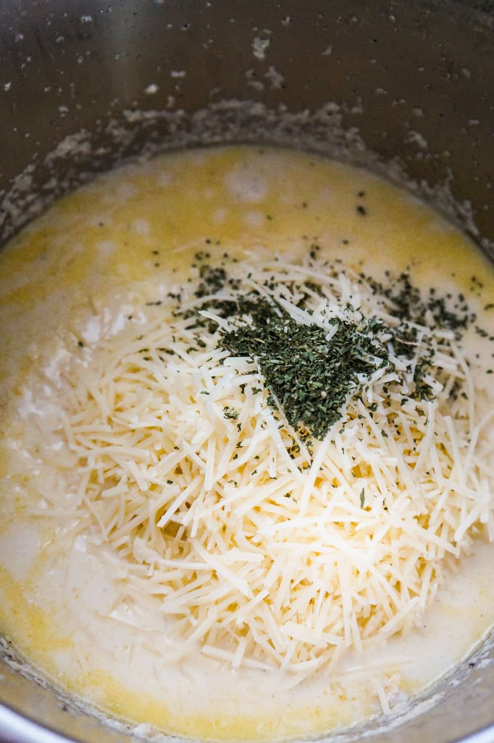 parsley flakes and shredded Parmesan cheese on top of creamy liquid in an Instant Pot
