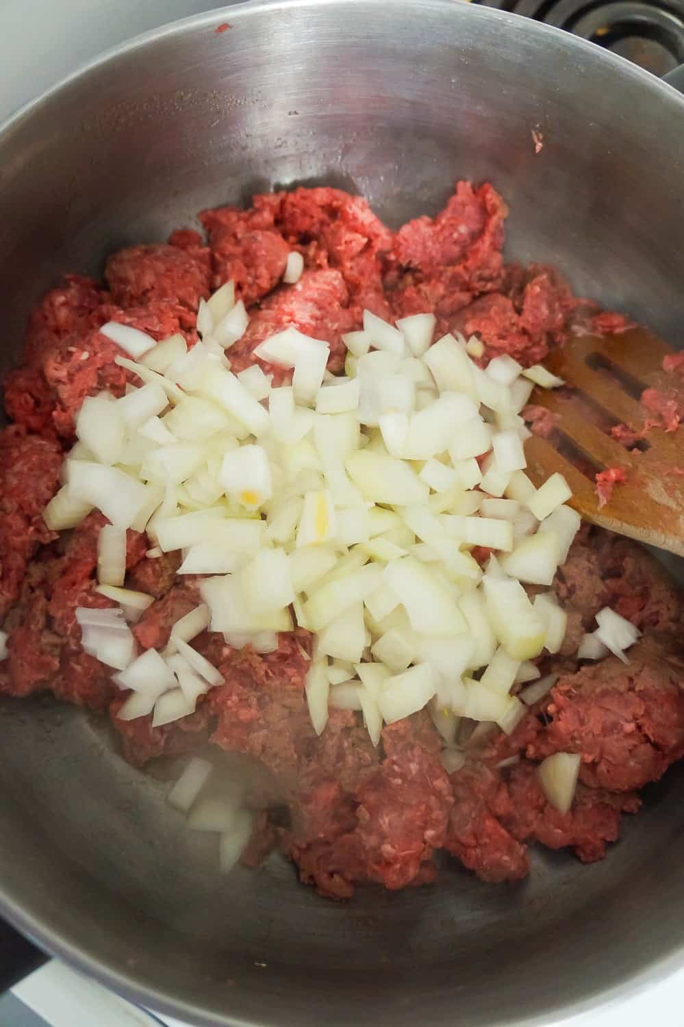 uncooked ground beef and diced onions in a large pot