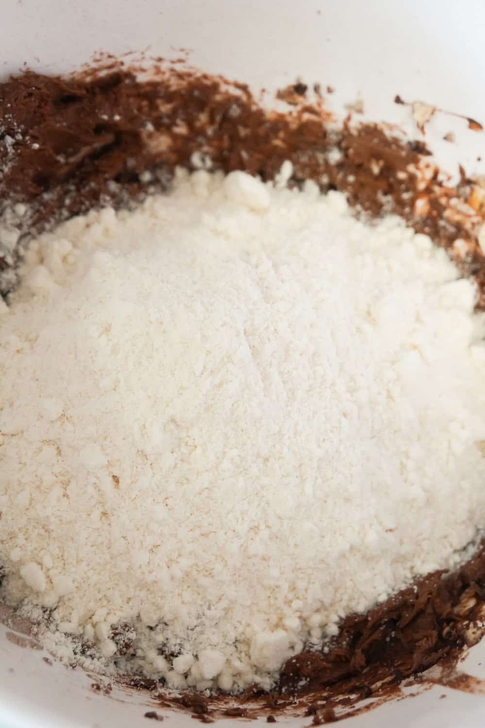 sugar cookie mix on top of chocolate pudding mixture in mixing bowl