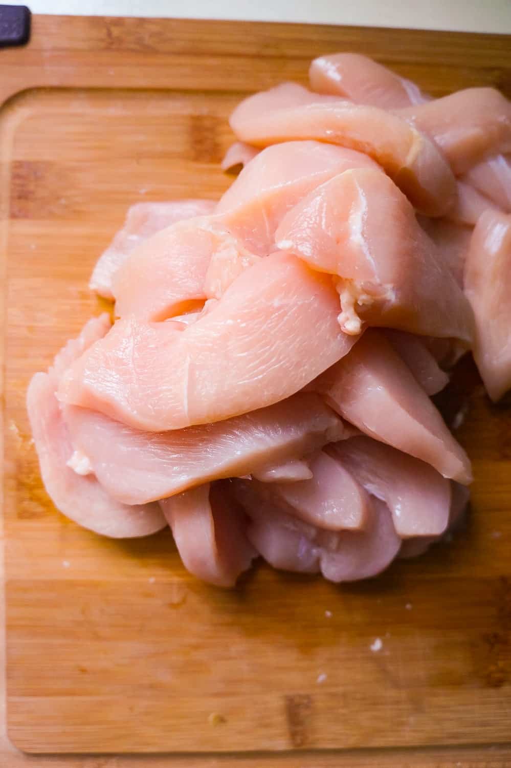 raw chicken breast slices on a cutting board