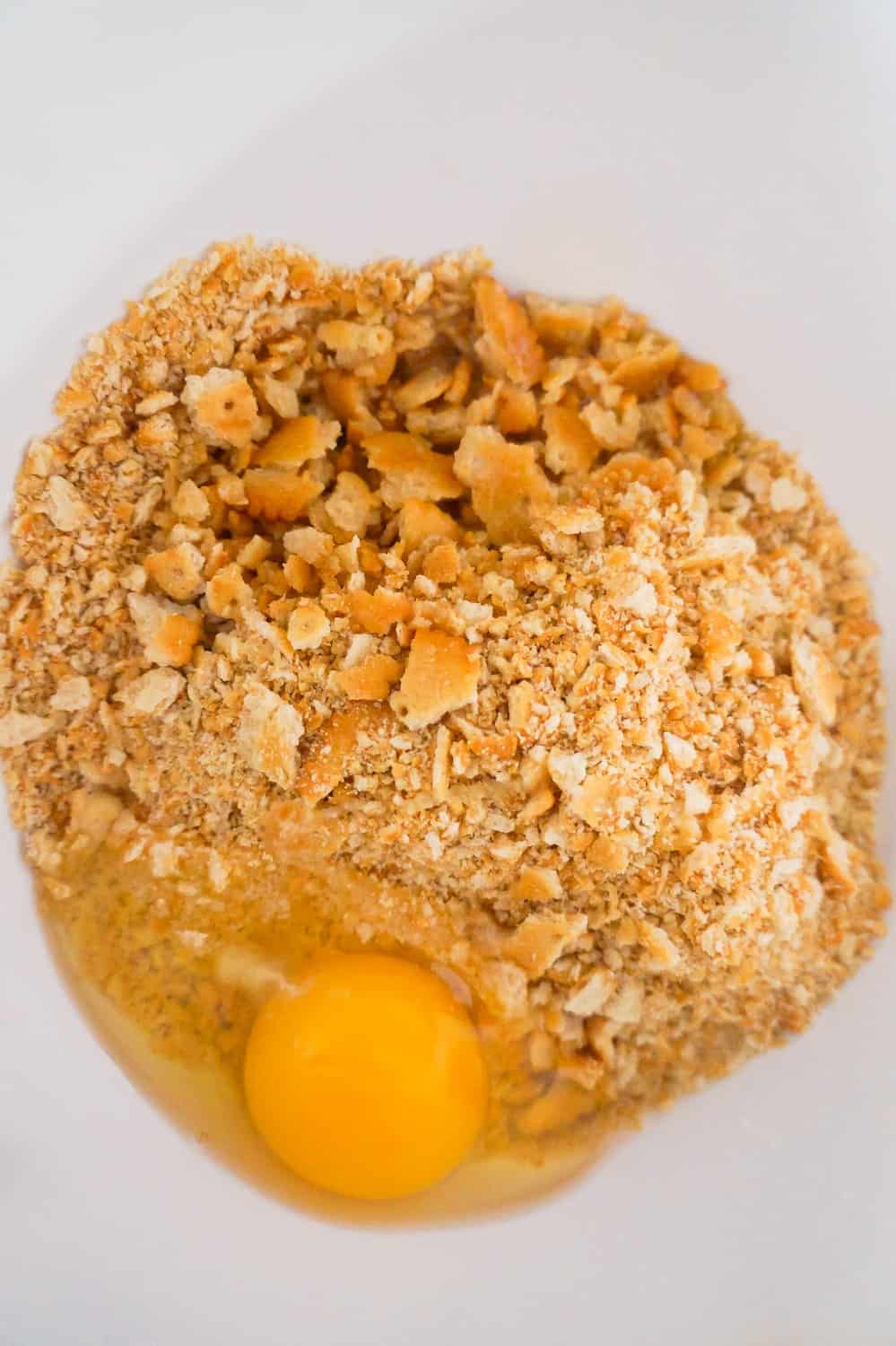 crumbled Ritz crackers, melted butter and an egg in a mixing bowl