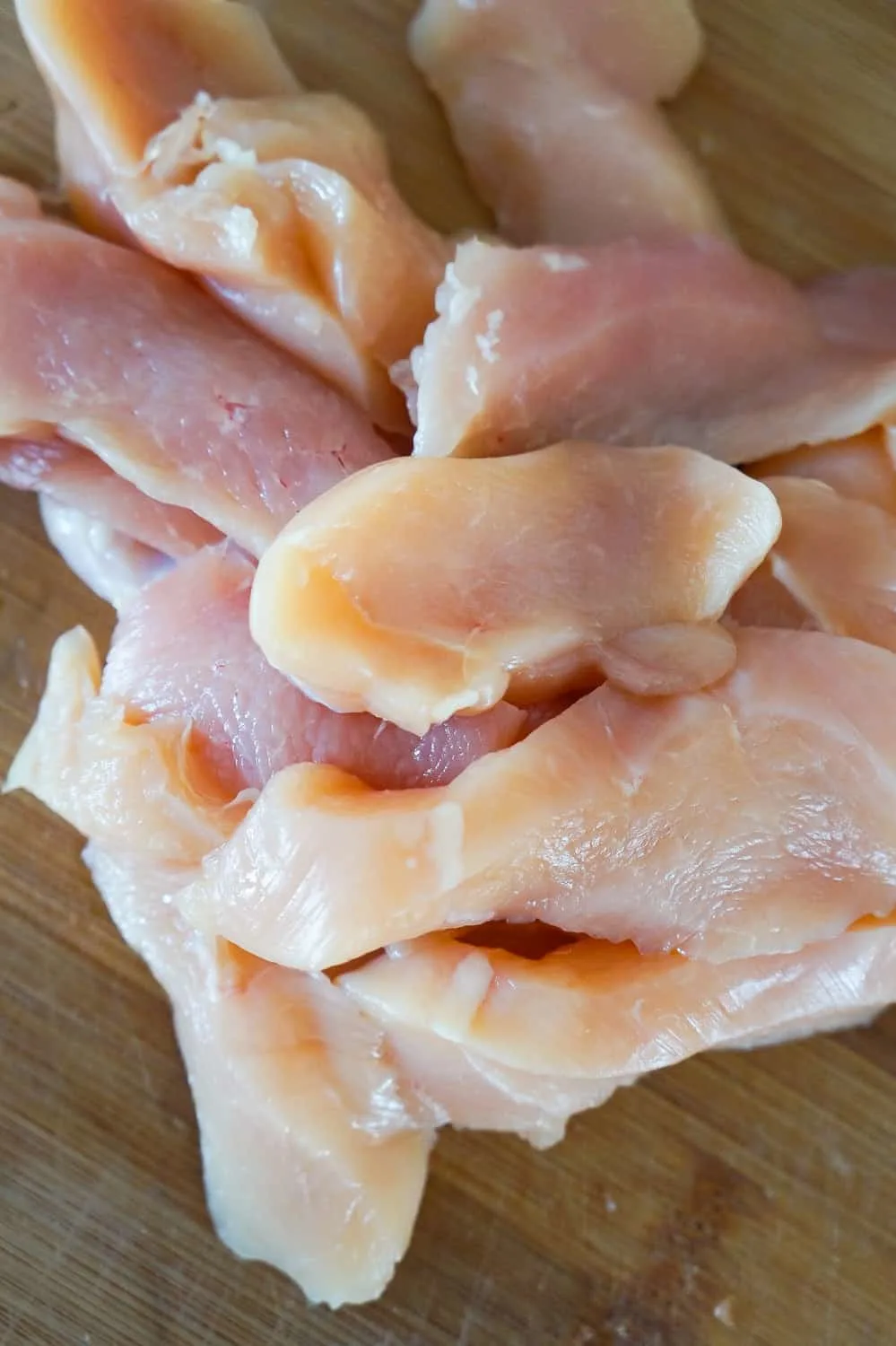 raw chicken breast slices on a cutting board