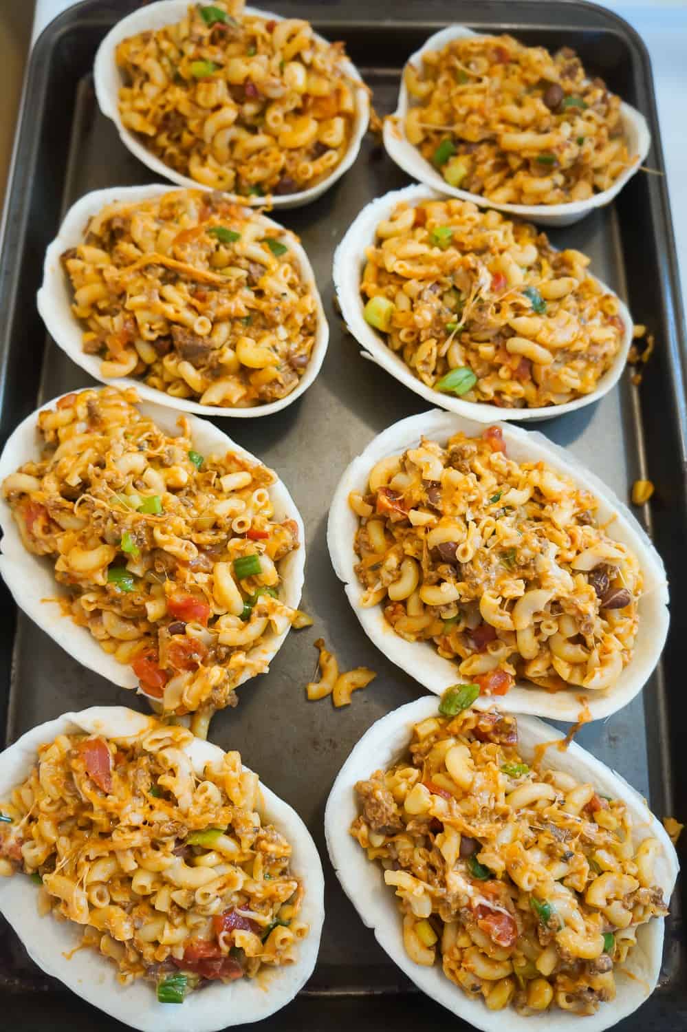 cheesy taco pasta in tortilla bowls on a baking sheet