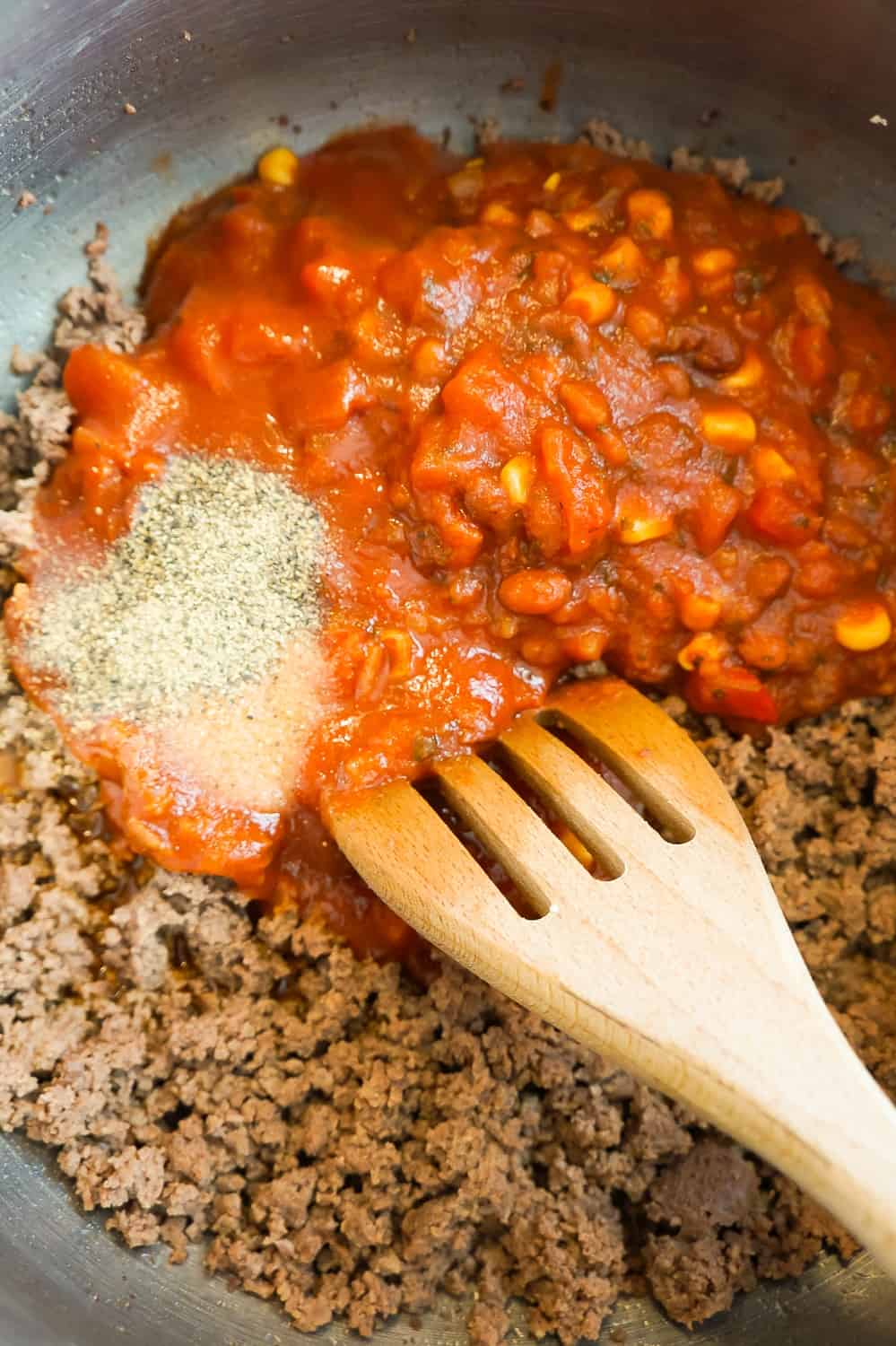 salsa and taco sauce poured over cooked ground beef in a pot