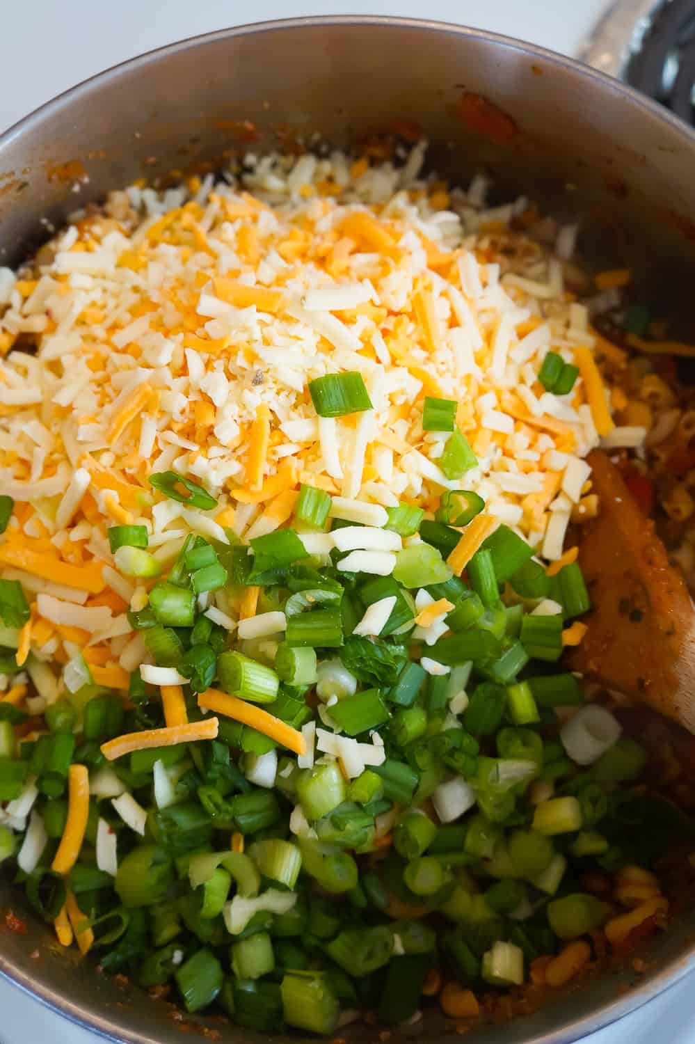 shredded nacho cheese and chopped green onions on top of macaroni