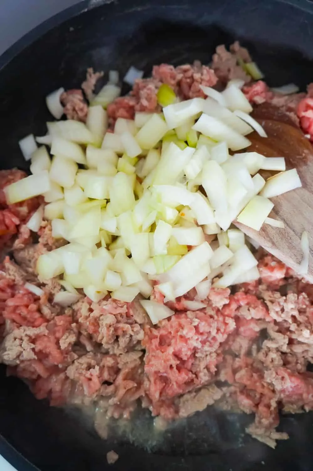 diced onions on top of ground turkey in a frying pan