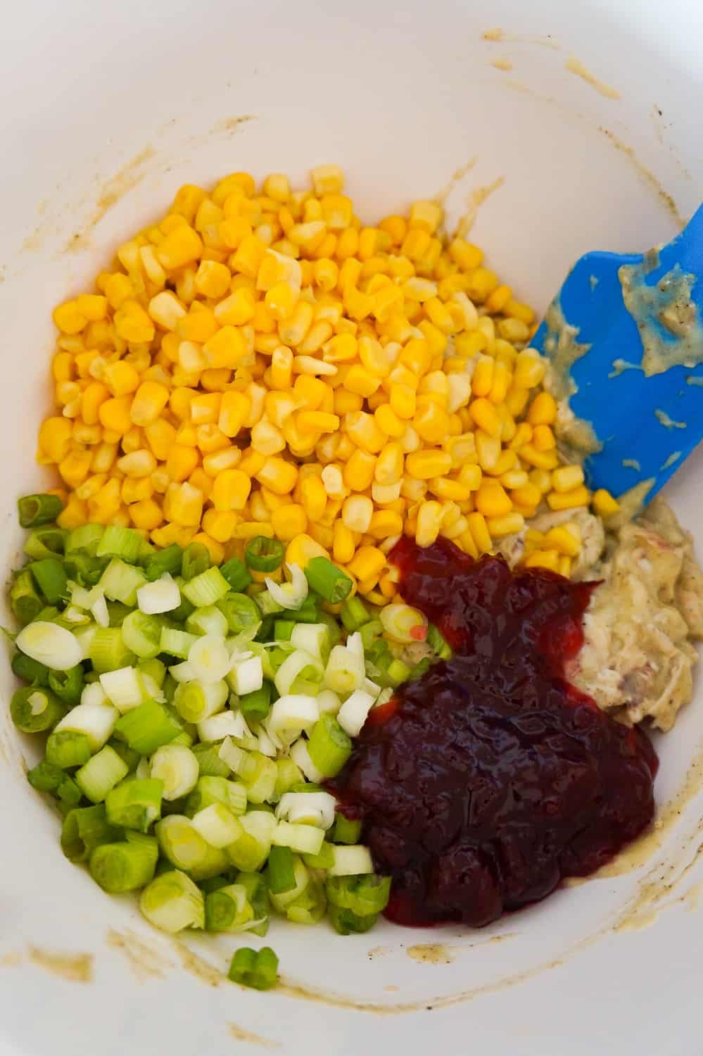 corn, chopped green onions, cranberry sauce and shredded chicken in a mixing bowl