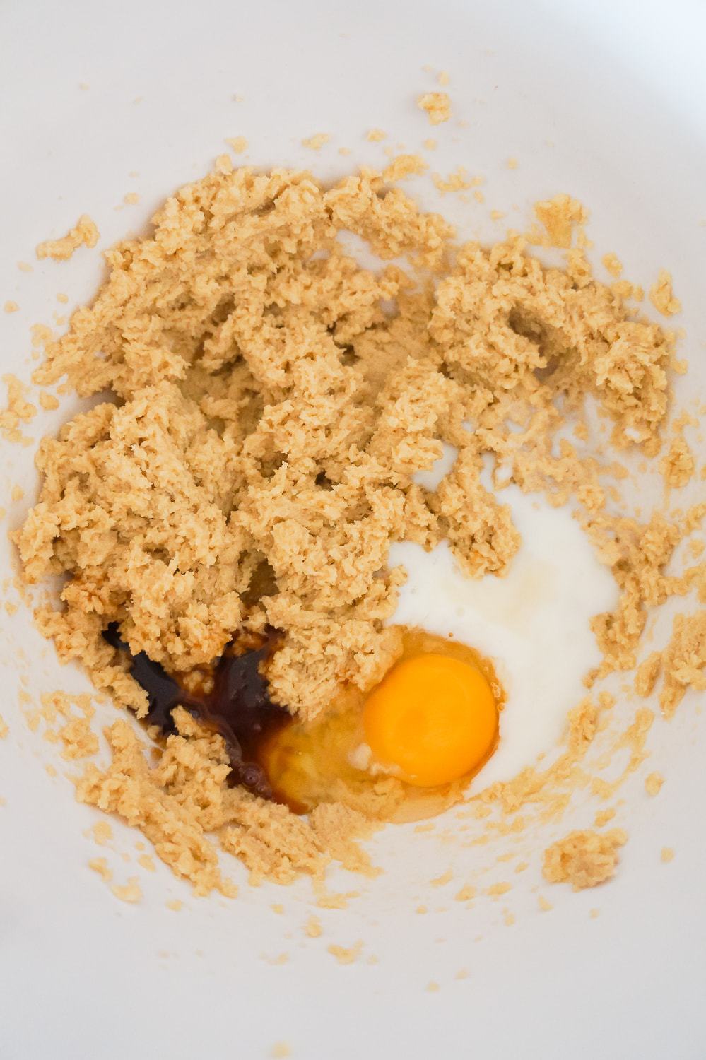 egg, milk and vanilla extract being added to a Crisco and sugar mixture in a mixing bowl
