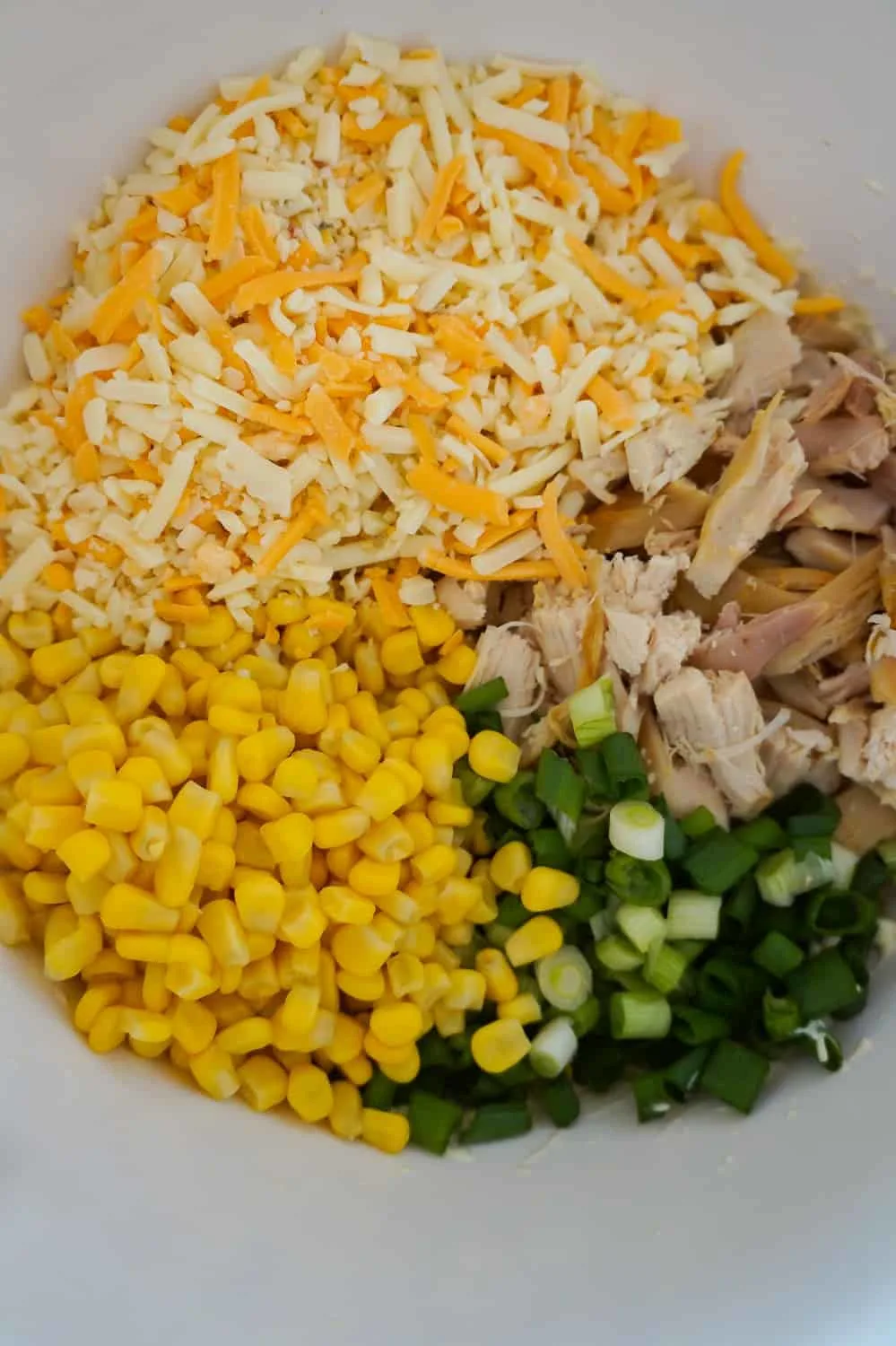 shredded cheese, corn, chopped green onions and shredded chicken in a mixing bowl