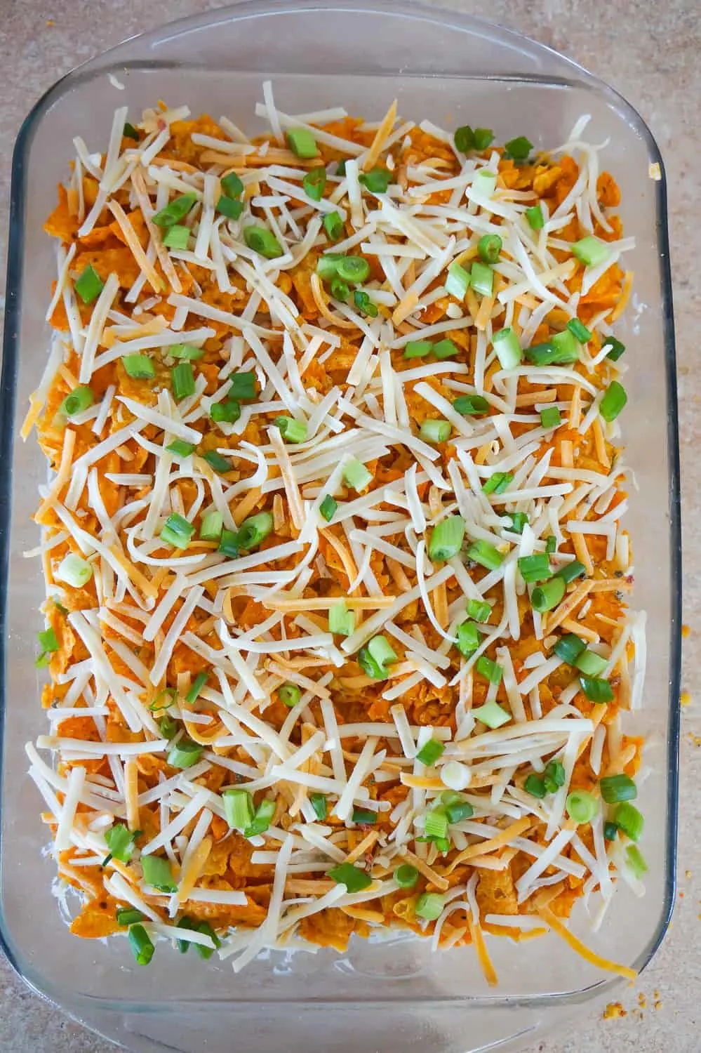 shredded cheese and chopped green onions on top of Doritos casserole before baking
