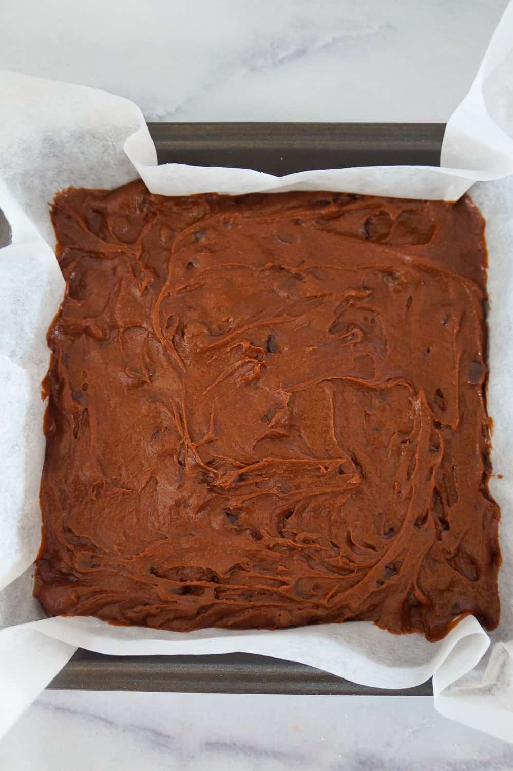 brownie batter in a parchment lined baking pan