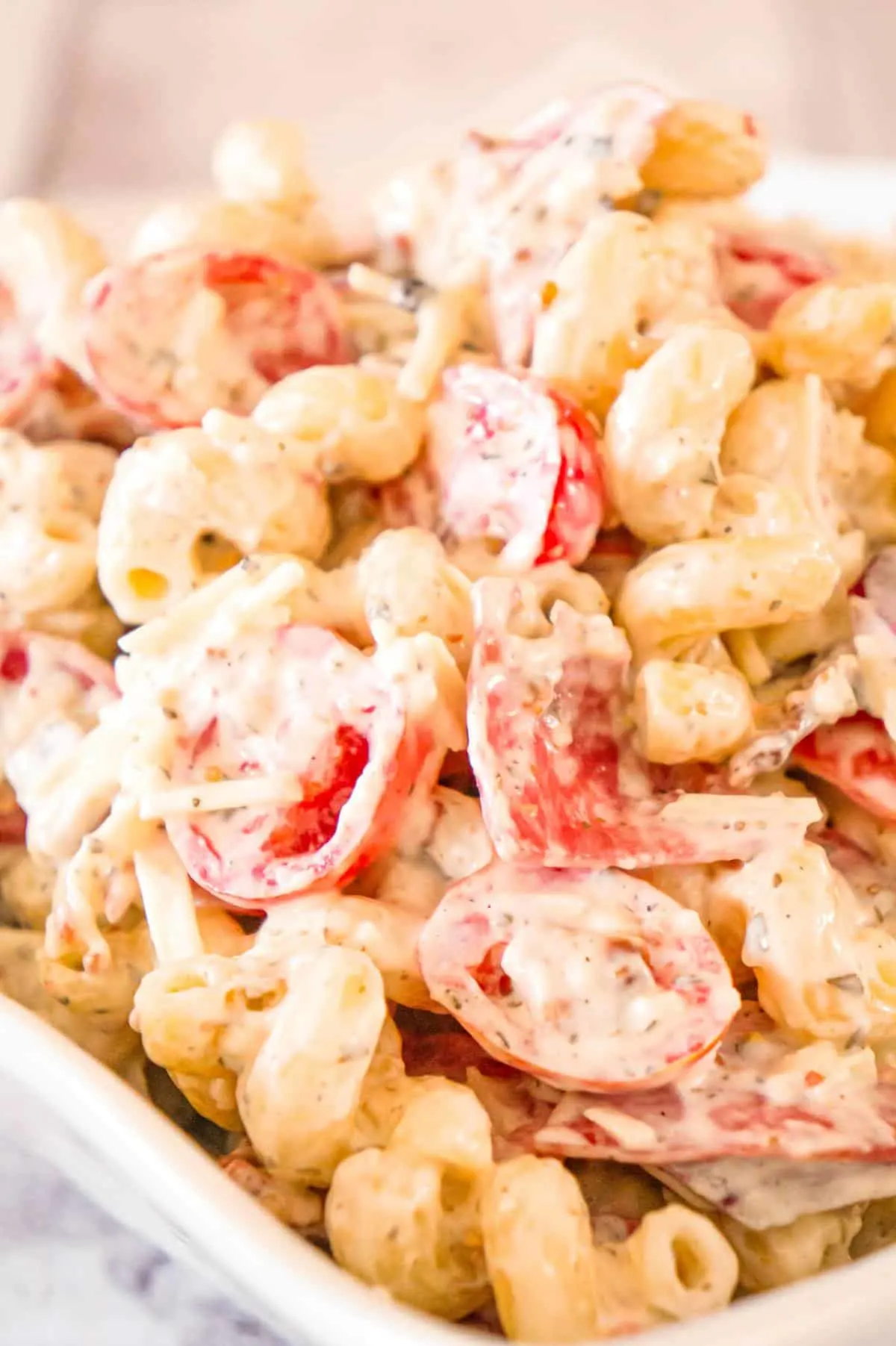 Italian Pasta Salad is a cold side dish recipe loaded with salami, chopped tomatoes, red onions, crumbled bacon, Parmesan cheese and mozzarella cheese all tossed in a creamy basil pesto dressing.