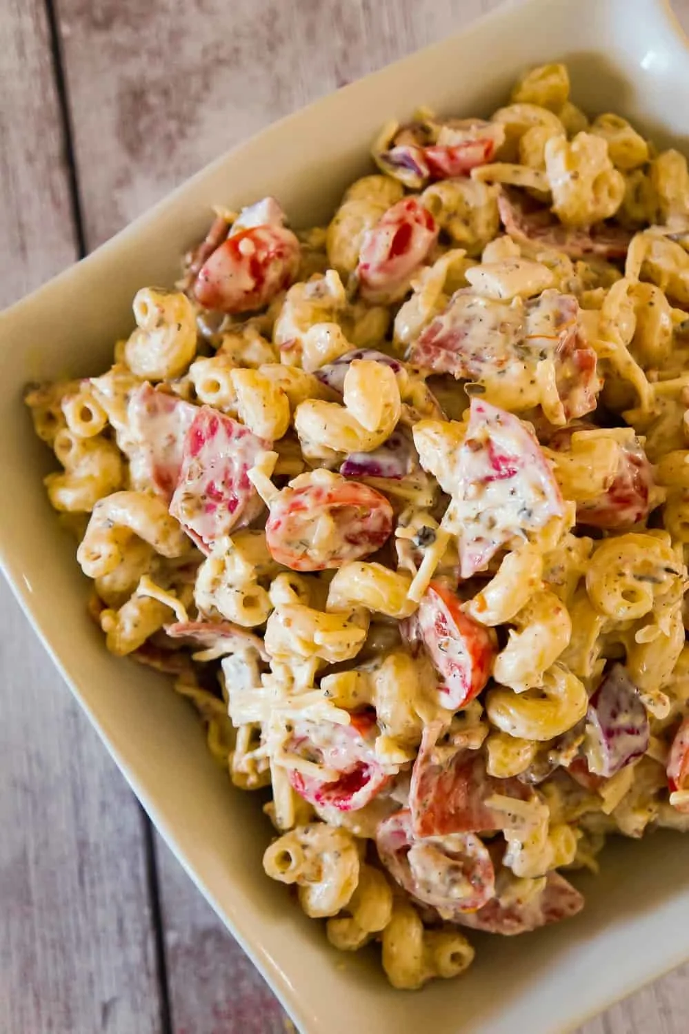 Italian Pasta Salad is a delicious cold side dish recipe perfect for potluck parties. This creamy pasta salad is loaded with cherry tomatoes, red onions, salami, bacon, basil pesto, Parmesan cheese and mozzarella cheese.