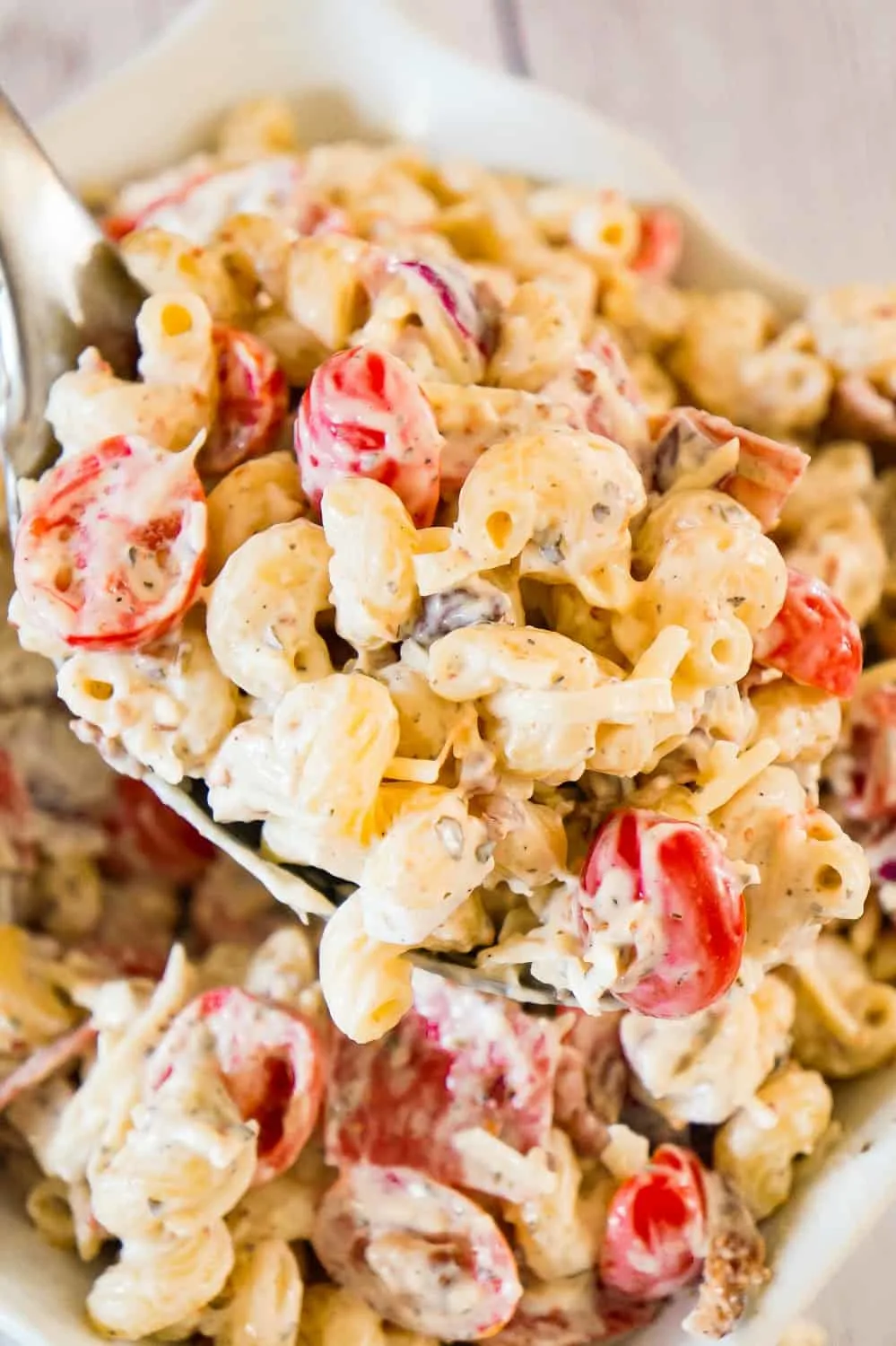 Italian Pasta Salad is a delicious cold side dish recipe perfect for potluck parties. This creamy pasta salad is loaded with cherry tomatoes, red onions, salami, bacon, basil pesto, Parmesan cheese and mozzarella cheese.