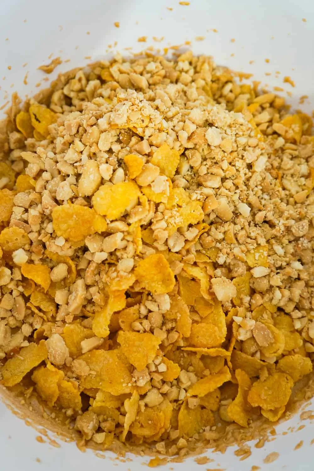 cornflakes and crushed peanuts in a mixing bowl