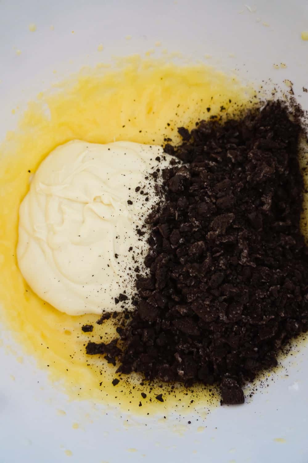 melted white chocolate and crushed Oreo cookies added to vanilla pudding mixture in mixing bowl