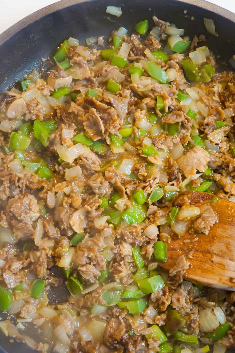 chopped roast beef, diced green pepper and diced onions in a frying pan
