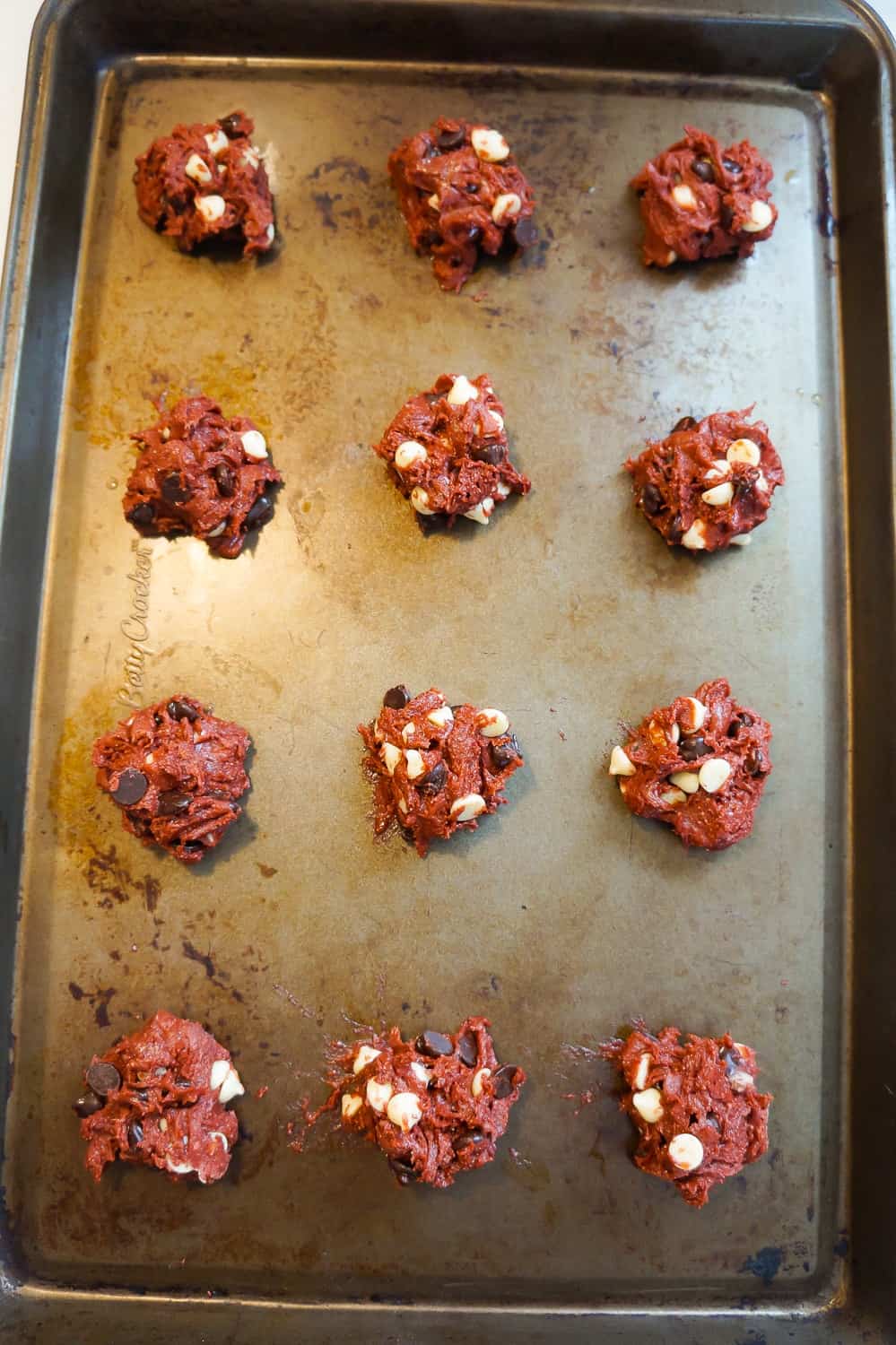 red velvet cookie dough balls on a baking sheet