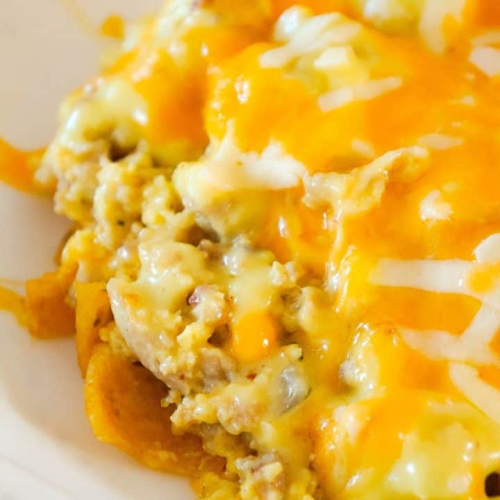 Breakfast Frito Pie is a fun twist on the classic Frito pie recipe that is perfect for serving at breakfast or dinner. This tasty dish starts with a layer of corn chips topped with scrambled eggs, sausage, bacon, Hollandaise sauce and melted cheese.