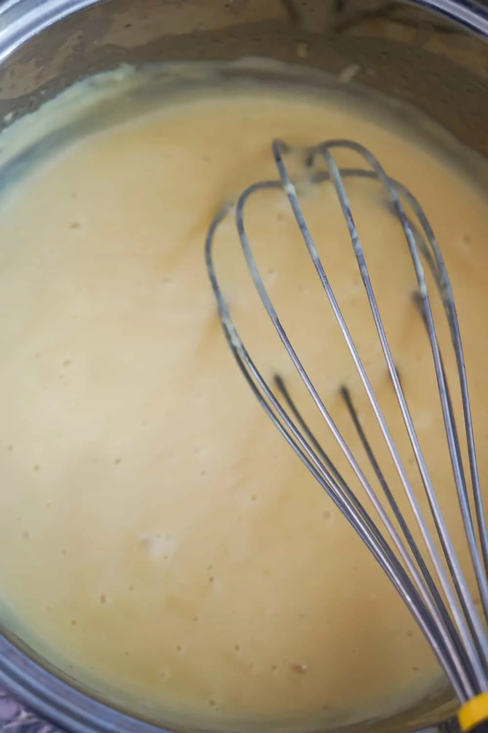 Hollandaise sauce in a pan with a whisk